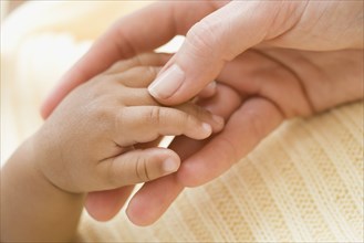 Close up of Hispanic mother and baby holding hands