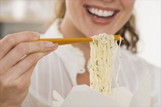 Close up of woman eating noodles with chopsticks