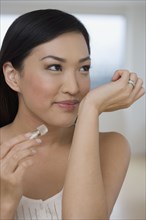 Asian woman smelling perfume on wrist