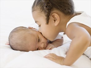 African girl kissing newborn baby sibling