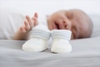 Close up of baby booties next to sleeping newborn baby