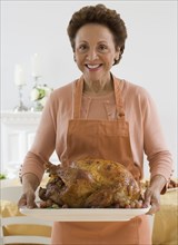 Senior Hispanic woman holding roast turkey