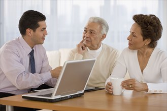 Hispanic businessman talking to senior couple in home