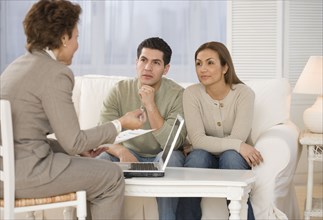 Hispanic businesswoman talking to couple in home