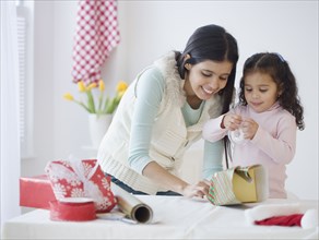 Hispanic mother and daughter wrapping gifts