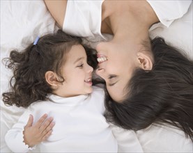 Hispanic mother and daughter smiling at each other