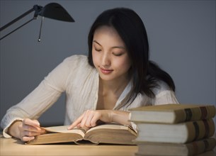 Asian woman reading at desk