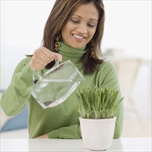 Indian woman watering potted plant