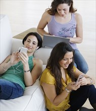 Three young women using wireless devices