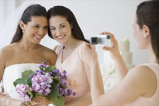 Hispanic bride and bridesmaid being video recorded