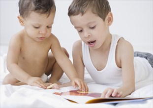 Hispanic boy reading to baby brother