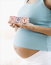 Pregnant African American woman holding 'BOY' blocks