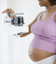 Pregnant African American woman standing on scale