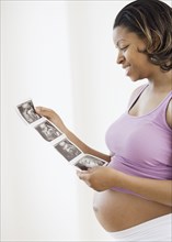 Pregnant African American woman looking at ultrasound printout