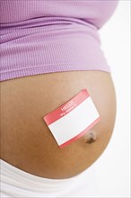 Pregnant African American woman with name tag sticker on belly