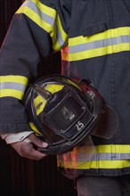 Hispanic male firefighter holding helmet
