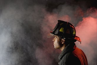 Hispanic male firefighter looking into smoke
