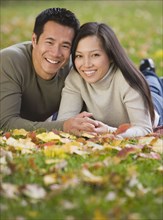 Asian couple laying in grass
