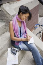 Mixed Race woman writing on steps
