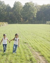 Hispanic sisters holding hands in field