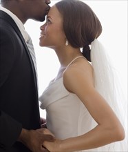 African groom kissing bride's forehead