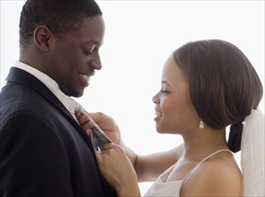 African bride adjusting groom's necktie