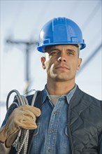 Hispanic male electrician carrying coiled wire