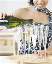 Mixed Race woman pouring champagne