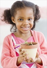 Mixed race girl holding seedling in pot