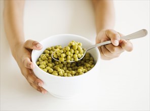 Close up of mixed race girl eating bowl of peas