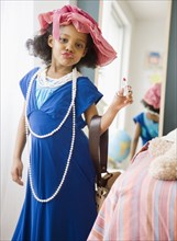 Mixed race girl playing dress-up in mother's clothes