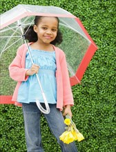 Mixed race girl with umbrella and flowers
