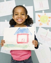 Mixed race girl holding water color painting of a house
