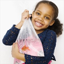 Mixed race girl holding goldfish in a bag