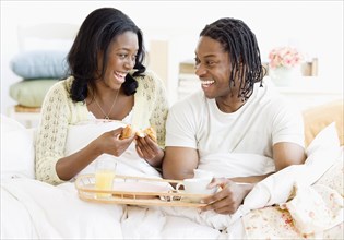 African couple eating breakfast in bed