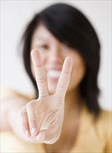 Close up of Asian woman making peace sign