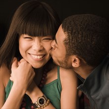 African man kissing Asian girlfriend