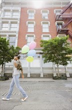 African woman walking with bunch of balloons