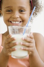 Mixed race girl holding glass of milk