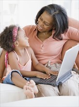 African grandmother teaching granddaughter how to use laptop