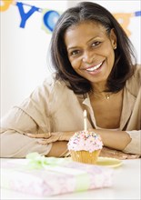African woman smiling with birthday candle in cupcake