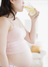 Pregnant Asian woman drinking water