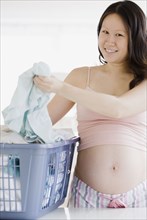 Pregnant Asian woman doing laundry