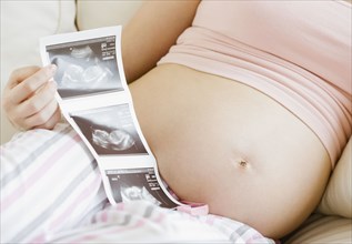 Pregnant Asian woman looking at ultra sound pictures