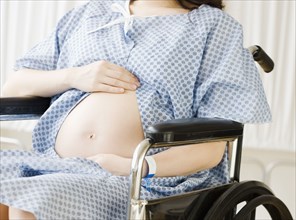 Pregnant Asian woman sitting in wheelchair at hospital