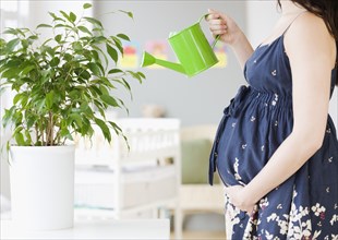 Pregnant Asian woman watering plants
