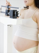 Pregnant Asian woman weighing herself
