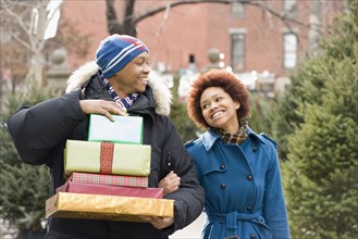 African man carrying stack of Christmas presents for girlfriend