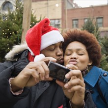 African man in santa hat taking self-portrait with girlfriend