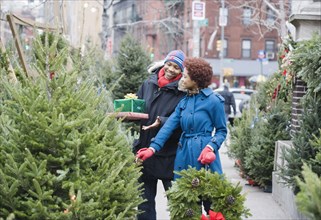 African man choosing Christmas tree with girlfriend
